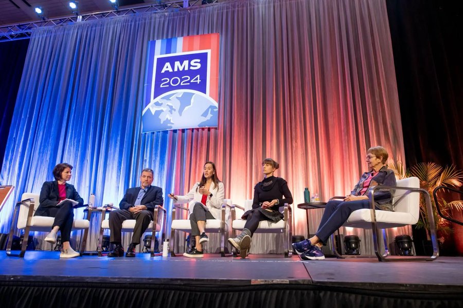 Bernadette Woods Placky on a five-person panel on stage beneath an AMS 2024 banner